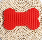 Red silicone bone shaped licking mat for dog treats and slow feeding
