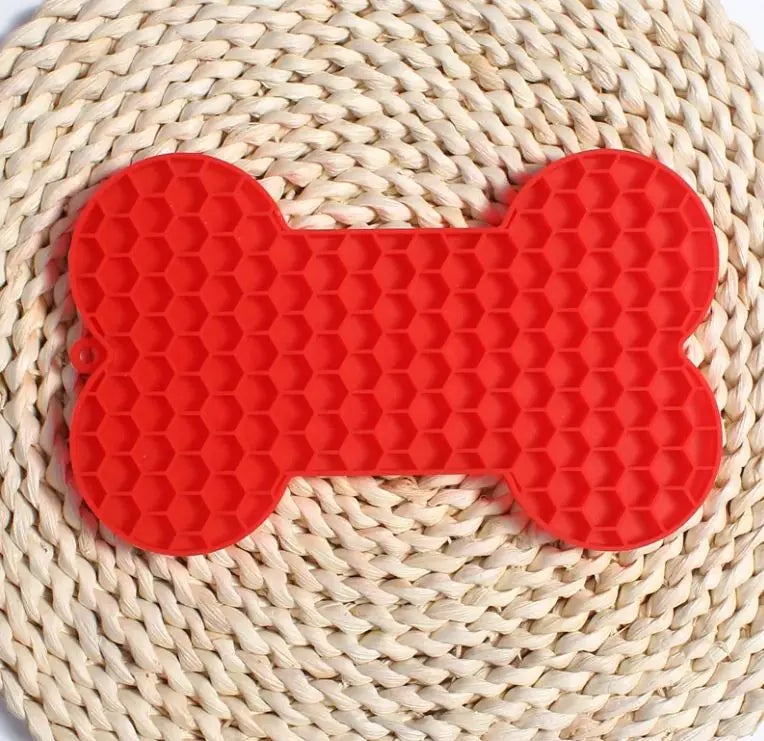 Red silicone bone shaped licking mat for dog treats and slow feeding
